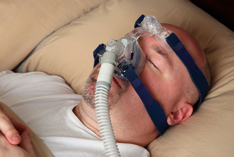 older heavy man sleeping with sleep apparatus on in their bed