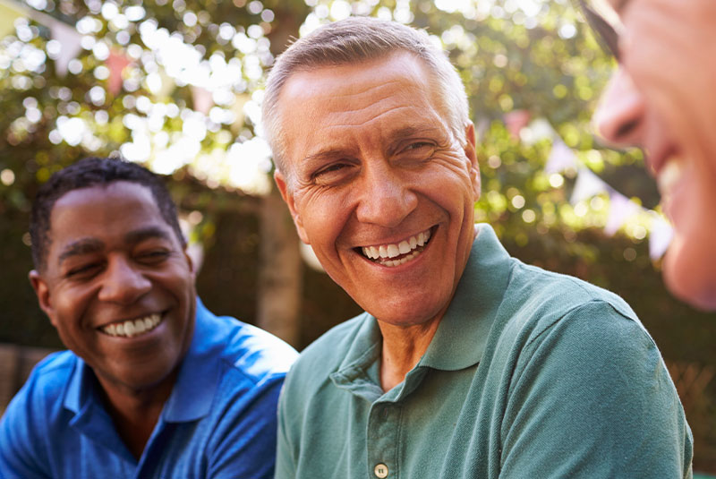 mature man smiling with friends confidently