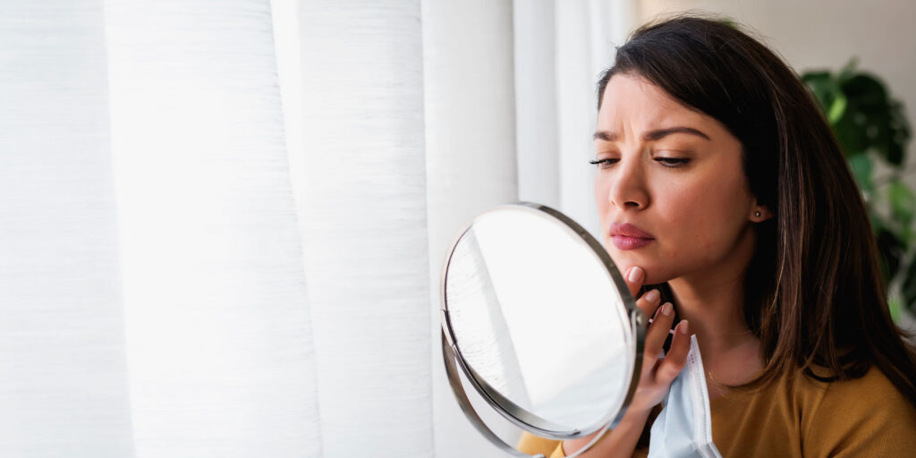 women looking in handheld mirror concern