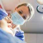 A side by side comparison of two sets of teeth. One set of teeth is severely damaged, while the other set of teeth has a full set of dental implants, looking perfect. No text on the image.